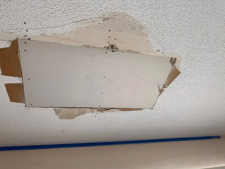 Drywall Repair — New drywall patch screwed into a textured ceiling
