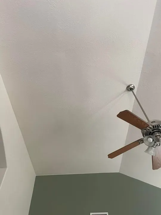Vaulted ceiling with a smooth drywall finish and ceiling fan