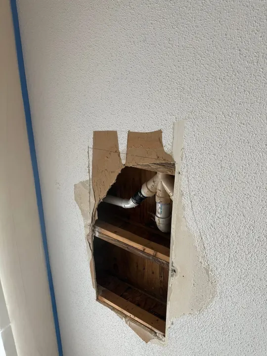 Hole cut in a textured wall for plumbing access
